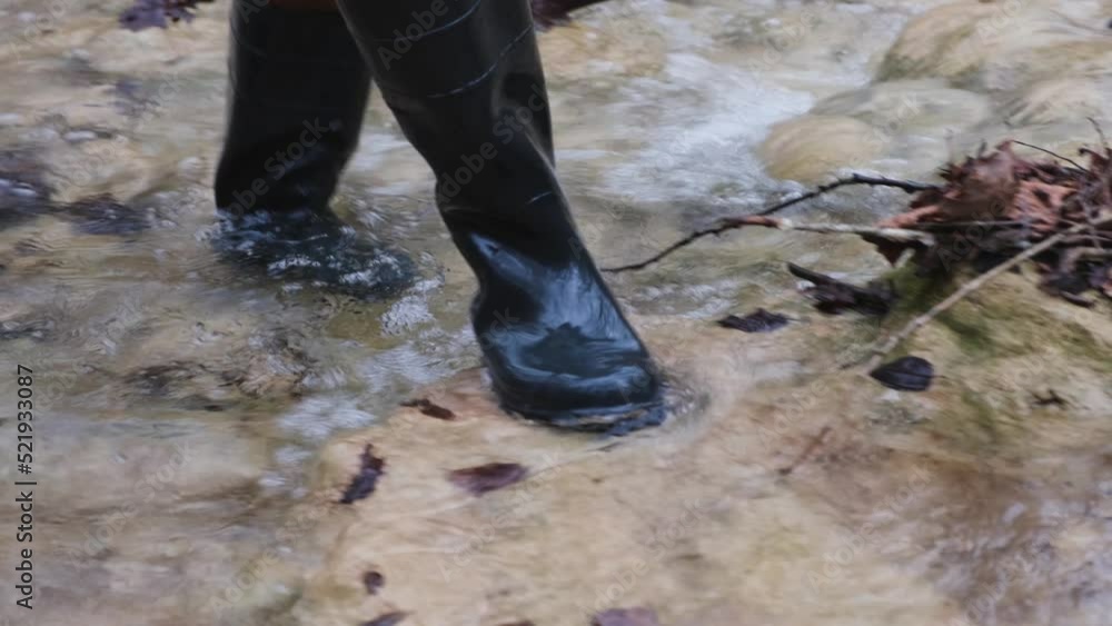Man rubber boots river. Washes boots in cold water. Spring hike in the forest. High khaki fishing boots. The concept of rural life, hiking. travel, outdoor recreation. Walking on a mountain river Man rubber boots river. Washes boots in cold water. Spring hike in the forest. High khaki fishing boots. The concept of rural life, hiking. travel, outdoor recreation. Walking on a mountain river