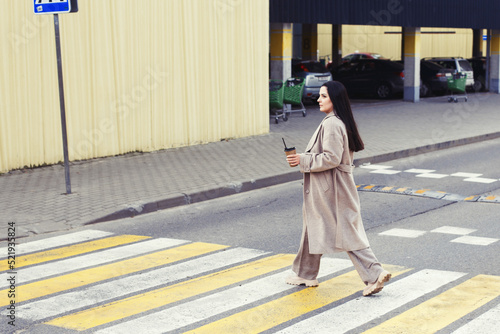 Wallpaper Mural woman holding coffee and crossing the road at pedestrian crossing against urban city background Torontodigital.ca
