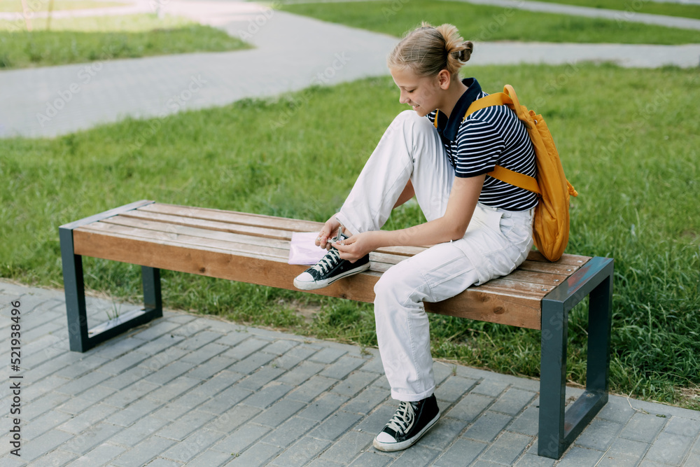 A cute teenage girl is sitting on a bench and tying her shoelaces A cute teenage girl is sitting on a bench and tying her shoelaces