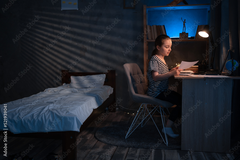 Teenage girl studying online at home looking at laptop at night. Home schooling. Social distancing. Online school test. e-learning Teenage girl studying online at home looking at laptop at night. Home schooling. Social distancing. Online school test. e-learning