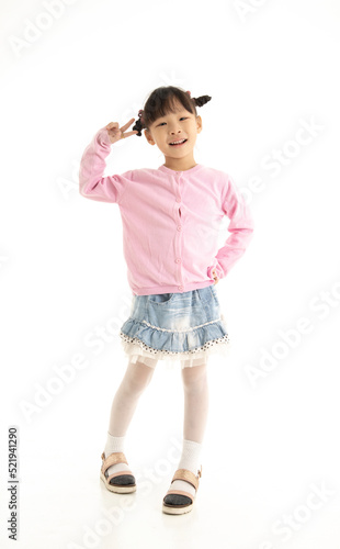 Full length of Little Asian girl standing and smiling over white background. © Aree