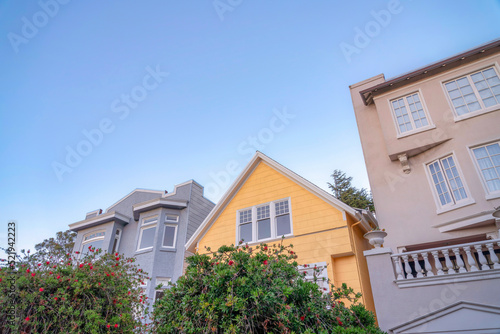 Yellow gable house in the middle of two houses with painted concrete wall exterior