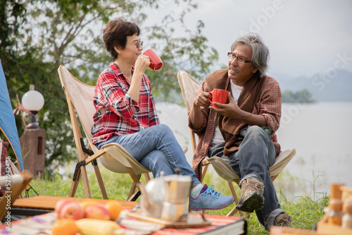 Happy retired couple having coffee together  by the tent in national park