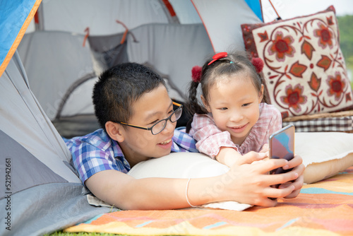 Happy asian siblings playing game together on a camping trip on a sunny day