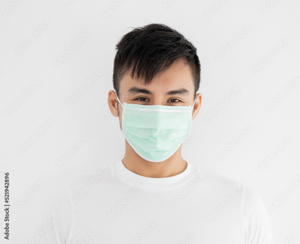 Young asian man wearing surgical mask over white background, healthcare and infection control concept.. Young asian man wearing surgical mask over white background, healthcare and infection control concept..