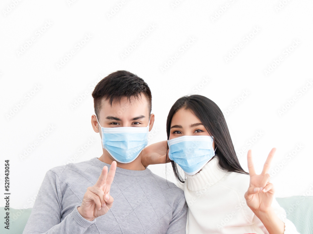 Young asian couple wearing surgical mask over white background, healthcare and infection control concept..