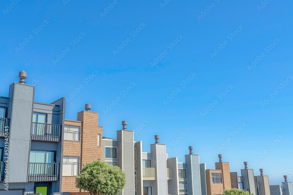Complex townhouses in a slope with chimney flues against the clear sky in San Francisco, California