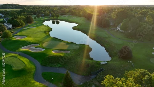 Beautiful aerial of golf course country club water hazard, sand trap, fairway green with reflection of sun. photo