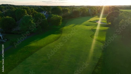 Aerial above golf course green fairway at sunset. Sand traps. Ball path tracking. photo