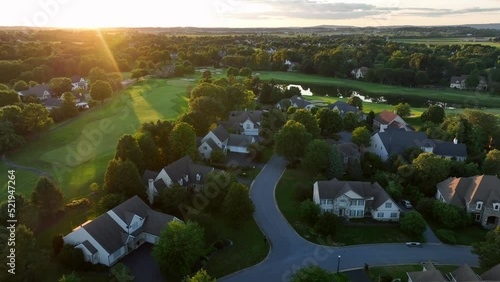 American golf course and country club. Manicured greens aerial truck shot at sunset. Homes with views of golf. photo