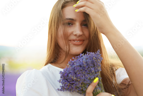 Close up portrait of a young woman holding bouquet of lavender whiile standing in lavender field photo