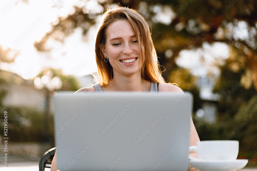 Happy beautiful young woman working on laptop in street cafe Happy beautiful young woman working on laptop in street cafe
