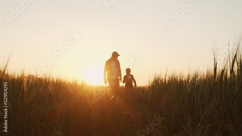Billede på lærred Farmer and his son in front of a sunset agricultural landscape