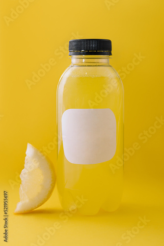 Bottle of fresh lemon juice on yellow background