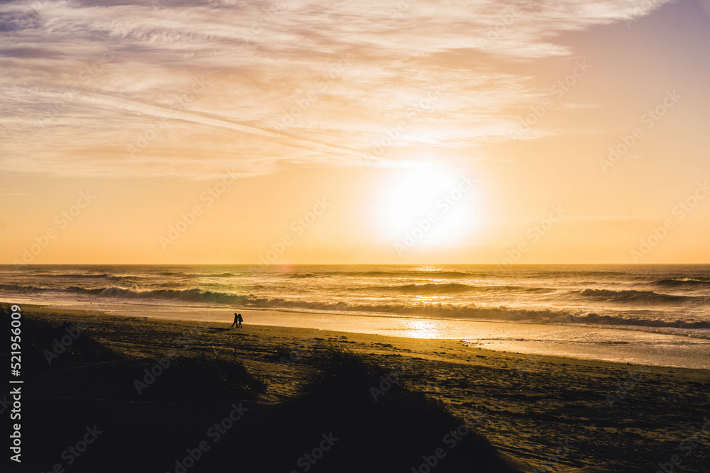 Aveiro, Portugal. People walking on the beach, surrounded by a suggestive sunset and ocean. Aveiro, Portugal. People walking on the beach, surrounded by a suggestive sunset and ocean.