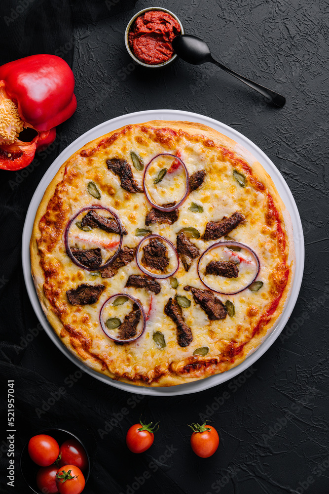 italian pizza with tomatoes, cheese, onions on black
