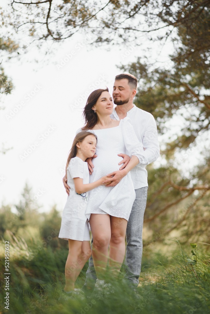 Pregnant woman and her daughter in the park at sunset. A happy family. Pregnant woman and her daughter in the park at sunset. A happy family.