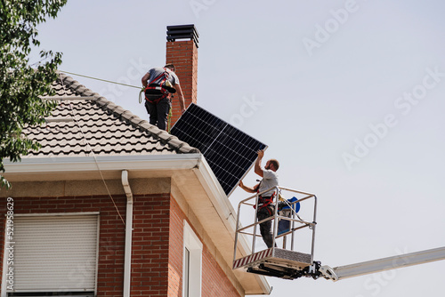 Technicians installing solar panels on rooftop photo