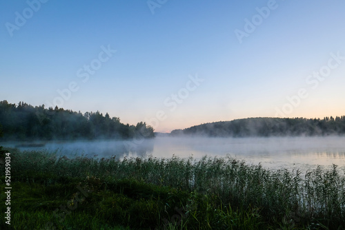 Very beautiful sunrise in summer over a foggy lake. Early morning in summer in nature. Defocused