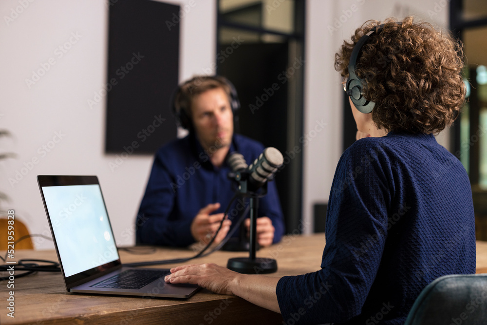 Presenter wearing headset interviewing guest in recording studio Presenter wearing headset interviewing guest in recording studio