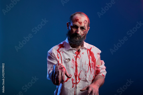 Portrait of halloween zombie with scars and bloody wounds posing in front of camera, dangerous undead corpse with scary scratches and creepy face in studio. Doomsday cruel monster devil.
