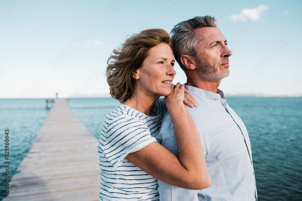 Smiling mature woman with hands on man's shoulder at jetty Smiling mature woman with hands on man's shoulder at jetty