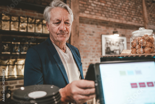 Senior businessman paying through smart phone at cafe counter photo