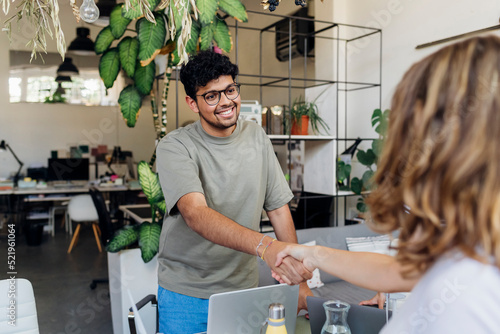 Businessman shaking hand with coworker at work place photo