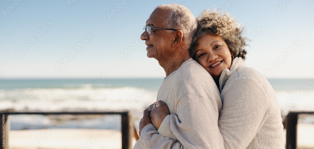 Obraz premium Romantic senior woman embracing her husband by the ocean