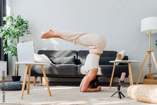 Woman practicing supported headstand pike yoga pose in online class