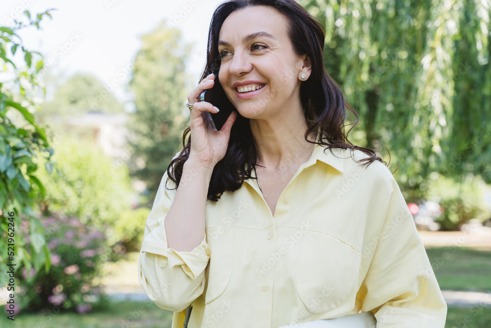 Happy woman talking on mobile phone in park Happy woman talking on mobile phone in park