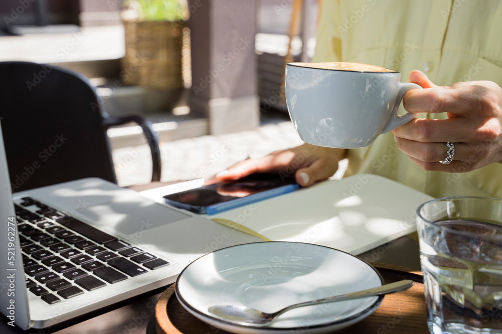 Hand of freelancer holding coffee cup at sidewalk cafe Hand of freelancer holding coffee cup at sidewalk cafe