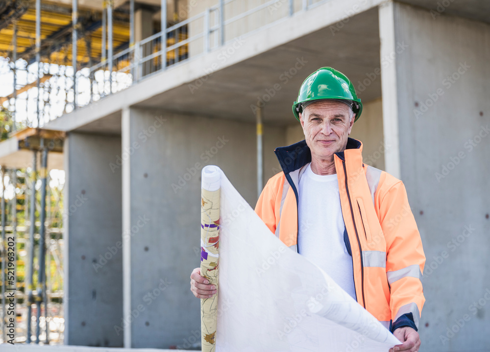Smiling senior construction worker with blueprint at site Smiling senior construction worker with blueprint at site