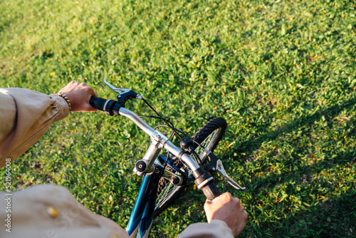 Hands of woman on handlebar riding bicycle in park