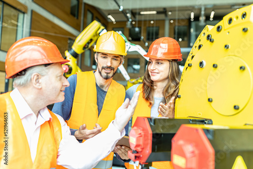 Male and female colleagues discussing robotic machine in industrial factory photo