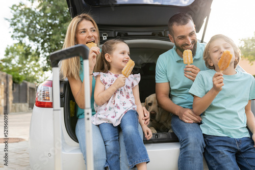 Happy family eating ice pops sitting in car trunk photo