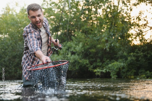 Fototapeta Naklejka Na Ścianę i Meble -  Fisherman hunting trouts in mountain river. Fishing net detail.