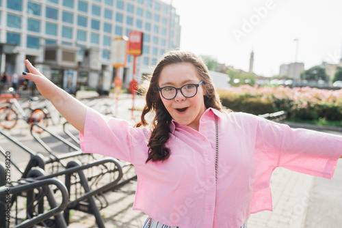 Happy teenage girl with down syndrome dancing on sunny day photo