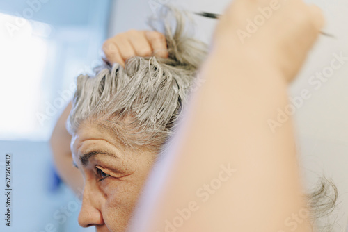 Senior woman applying hair dye at home photo