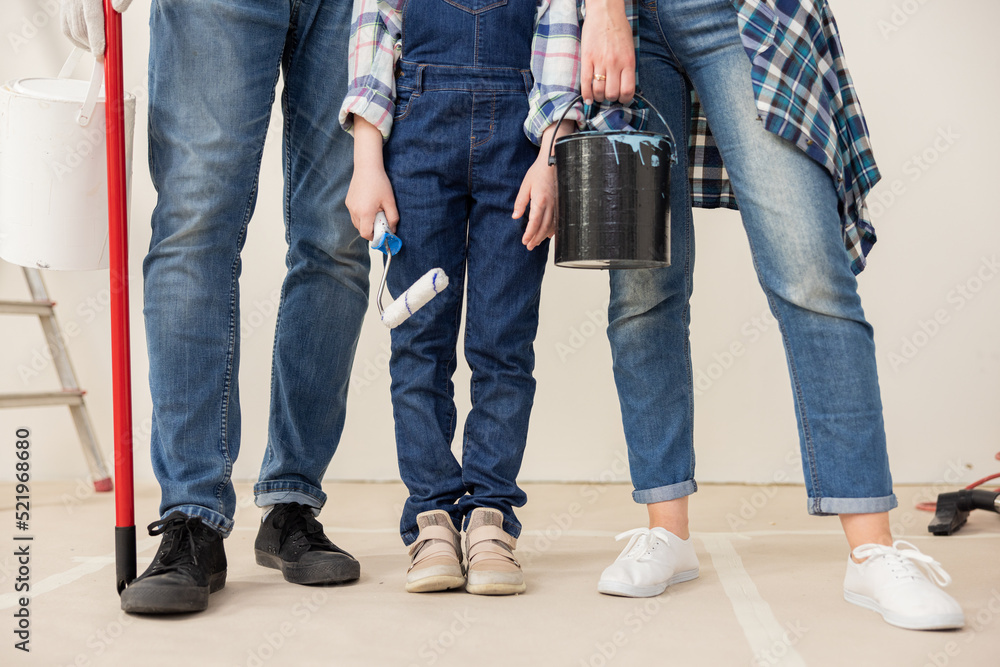 Close-up of the legs of three people who are dressed in denim style. All are wearing comfortable, sports shoes. In hands they hold the things they need for repair. there is a ladder in background. Close-up of the legs of three people who are dressed in denim style. All are wearing comfortable, sports shoes. In hands they hold the things they need for repair. there is a ladder in background.