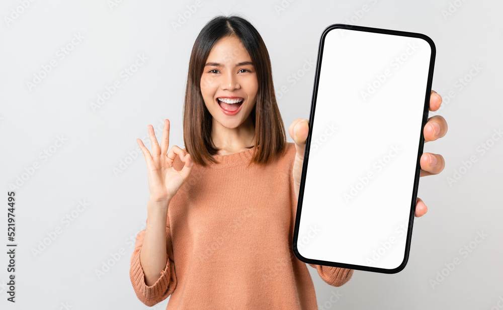 Foto Stock Beautiful Asian woman holding smartphone mockup of blank screen  and shows ok sign on grey background | Adobe Stock