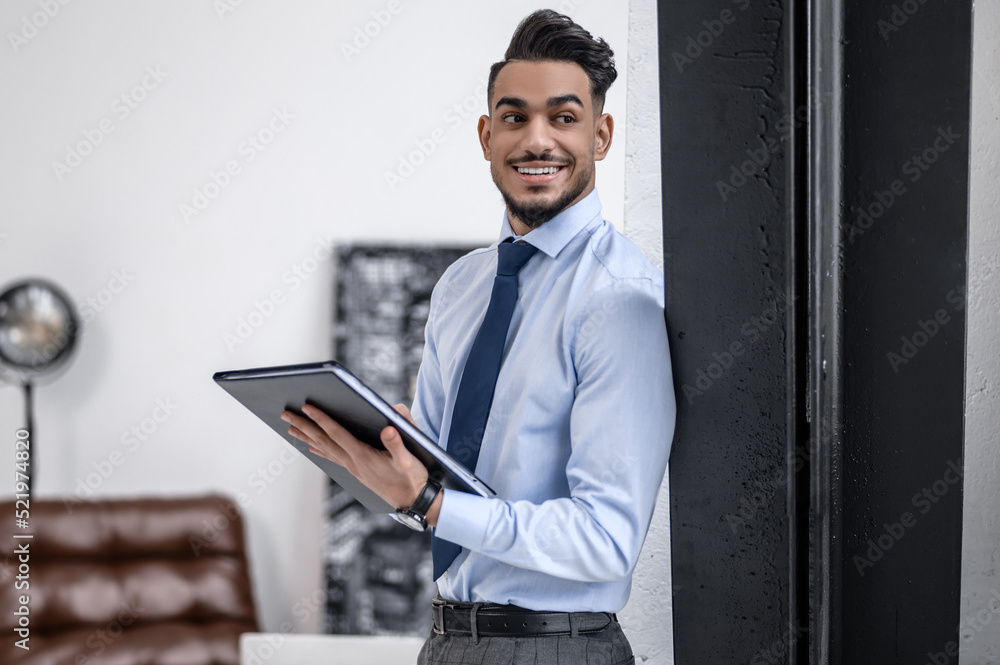 Man with folder smiling aside standing indoors