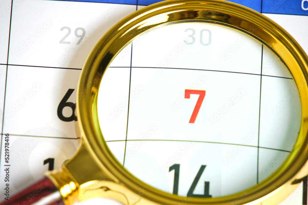 Calendar with number seven under magnifying glass. Calendar with number seven under magnifying glass.