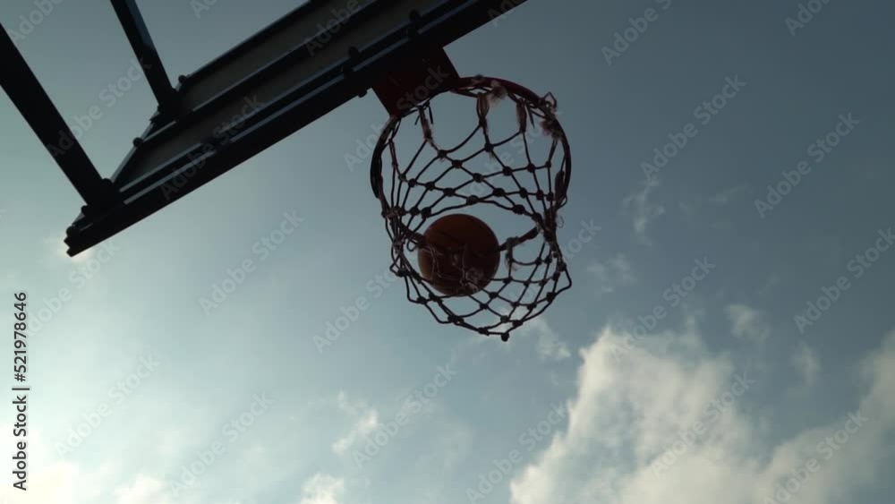 Failed attempt of basketball shot as ball miss the basket after bouncing off. High contrast ball flies against perfect cloudy sky in slow motion. Bad day. Miss target Failed attempt of basketball shot as ball miss the basket after bouncing off. High contrast ball flies against perfect cloudy sky in slow motion. Bad day. Miss target