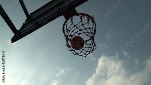 Failed attempt of basketball shot as ball miss the basket after bouncing off. High contrast ball flies against perfect cloudy sky in slow motion. Bad day. Miss target