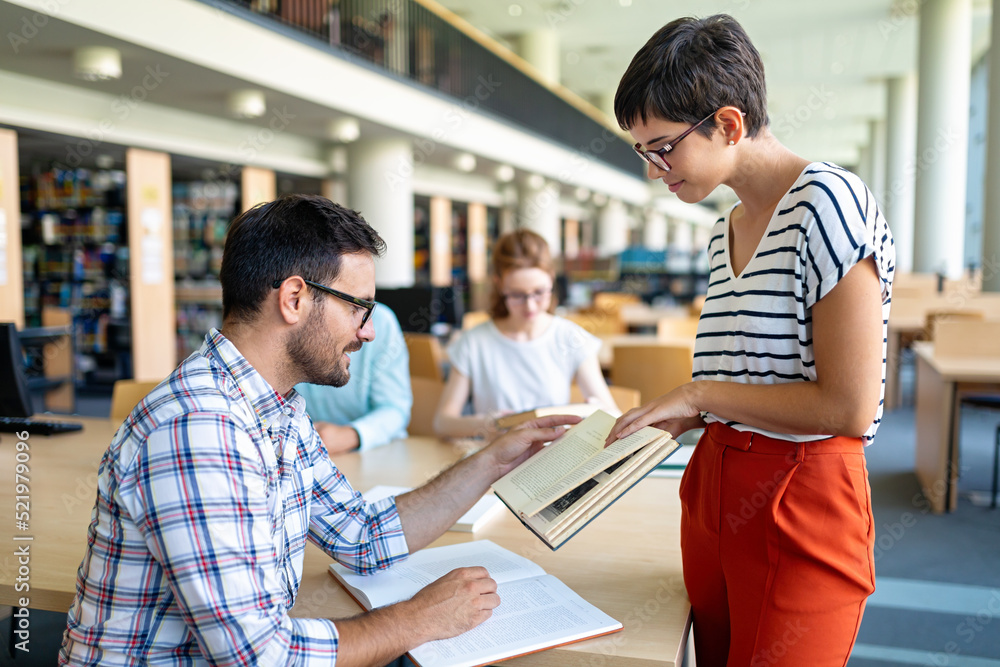 Happy university students studying with books in library. Group of multiracial people in college Happy university students studying with books in library. Group of multiracial people in college