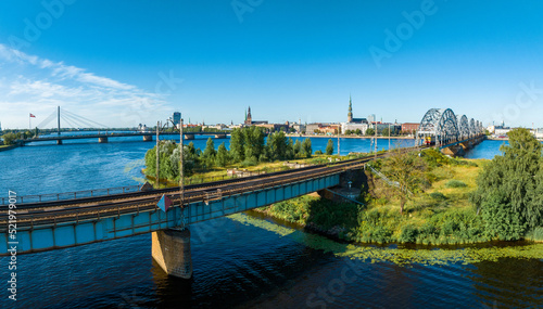 A bridge over river Daugava in Riga with a train passing by. Bridges in Latvia. Aerial Riga view.