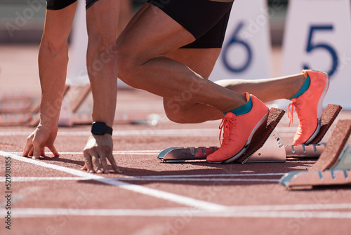 Man in a start block on an athletic track. A sprinter in a track and field race is poised at the starting line waiting for the start