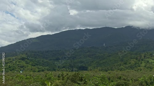 Natural nature view, calming shot of green silhouetted mountain, wind mill at the top and darkened cloud above photo