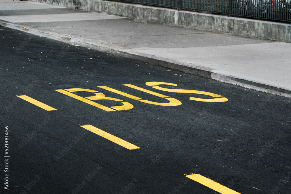 Obraz premium Bus text by big yellow letters on asphalt road at urban street